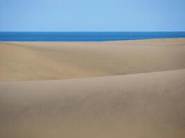 Sand textured pattern with copy space close up in Maspalomas, Gran Canaria. Abstract background wallpaper. Sand waves in a desert dune at the background of the sea photo
