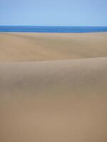 Sand textured pattern with copy space close up in Maspalomas, Gran Canaria. Abstract background wallpaper. Sand waves in a desert dune at the background of the sea photo