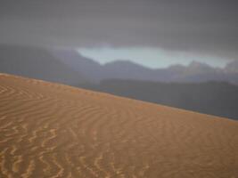 Sand textured pattern with copy space close up in Maspalomas, Gran Canaria. Abstract background wallpaper. Sand waves in a desert dune against the sky photo