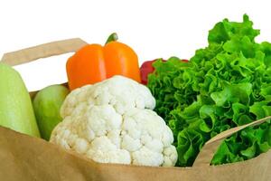 Fresh food vegetables donation isolated on background in paper bag package. Healthy food delivery during coronavirus. photo