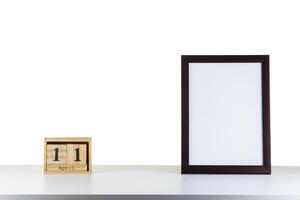 Wooden calendar 11 april with frame for photo on white table and background