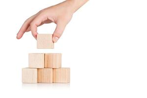 wooden cubes in the form of a pyramid with a hand on an isolate white background photo