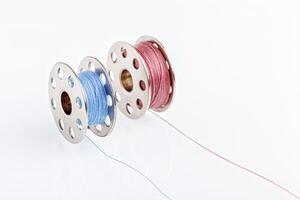 spools of blue and pink thread on a white background photo