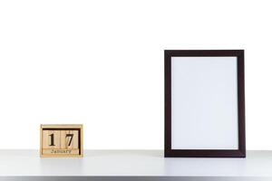 Wooden calendar 17 January with frame for photo on white table and background