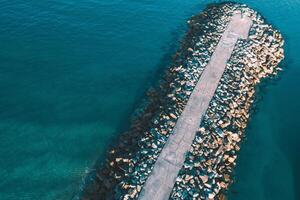 Breakwater of large granite blocks in a harbor at sunset as seen from a drone, aerial photograph photo