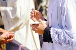 a catholic priest administering the sacrament of communion to attendees of an outdoor service photo