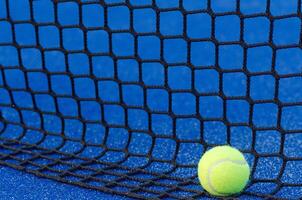 a ball at the base of a padel court net, racket sport background concept photo