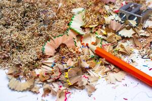 Colorful pencil shavings and sharpened tools scattered across a workspace filled with creative remnants in bright daylight photo