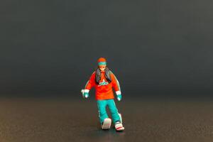 Miniature figurine of a skier is detailed with vibrant colors, set against a dark blurred background photo