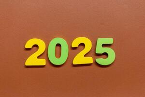 Colorful numbers 2025 on a brown textured background photo