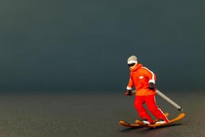 Miniature figurine of a skier is detailed with vibrant colors, set against a dark blurred background photo