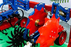 A blue tractor with red tires sits on a green field photo