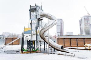 An urban playground with a snowy slide and tower in the city photo