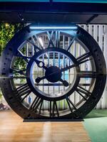 A clock with roman numerals sits on a wooden floor photo