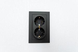 Rectangle wall plate with black double electrical outlet on white wall photo