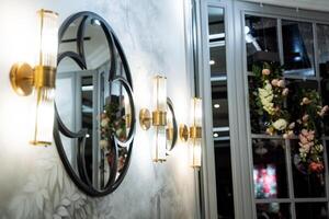 A round mirror is a fixture on a wall beside a window photo