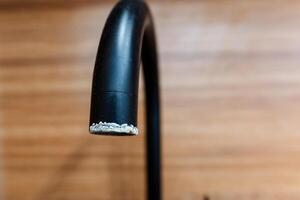 Close up of a black faucet on hardwood flooring with varnish photo
