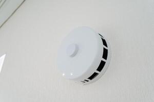 White smoke detector, hanging on wall, blends with wood, metal, circle design photo