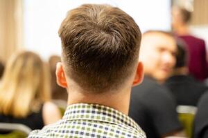 A man in a plaid shirt sits with others in a classroom photo