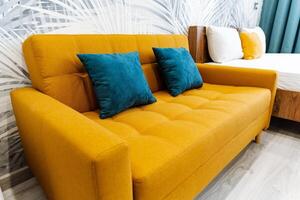 a yellow couch with blue pillows in a bedroom next to a bed photo