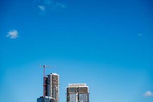Skyscraper under construction with crane, against a backdrop of blue sky photo