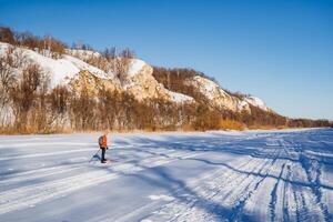 Beautiful winter landscape, man standing on snow in the middle of a frozen lake, sunny weather, long shadows. photo