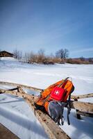 A backpack and first aid kit on a snowy wooden fence under a freezing winter sky photo