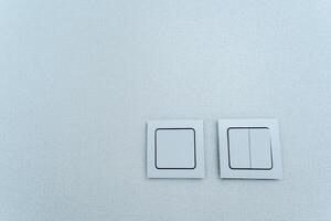 Two rectangular electric blue switches with a brand logo on a white ceiling photo