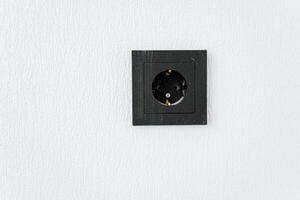 A rectangle black wall socket on a white wall, a stylish metal fashion accessory photo