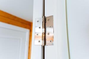 Close up of a hardwood door hinge on a white door with wood stain and varnish photo