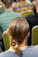 This captivating image highlights the rear view of a person with beautifully styled long hair fashioned into a ponytail while at a lively event photo
