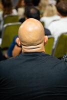 A bald man leads a conference, engaging an attentive audience and passionately promoting collaboration and learning among participants photo