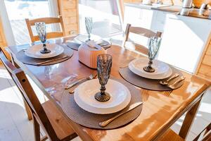 Beautiful hardwood dining table set with plates, glasses, and silverware photo