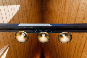Three lights hang from the wooden ceiling of a building photo