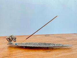 A silver metal incense holder with a bird on it photo