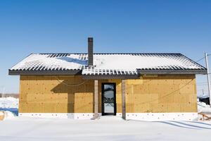 A small house with a roof made of wood photo