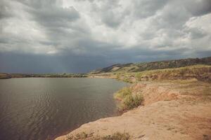 A serene lake under a cloudy sky, framed by majestic mountains in the background photo