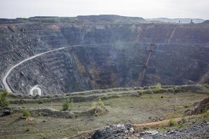 Road cuts through a massive canyon with towering peaks and rugged terrain photo