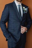 An elegant groom dressed in a modern suit adorned with floral decorations stands out beautifully against a warm, inviting background photo