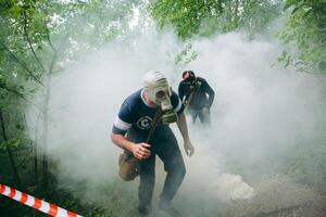 Man in gas mask flees through foggy forest, eerie mist surrounds tall trees photo