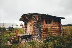 a small wooden cabin is sitting in the middle of a grassy field photo