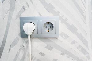 a white plug is plugged into a wall socket photo