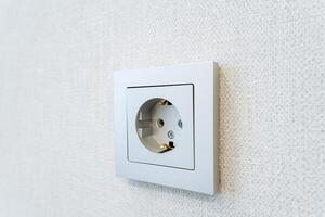 A white wall socket on a white wall, blending in seamlessly with the room photo