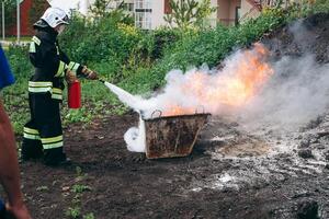 A firefighter is extinguishing a blazing fire with a fire extinguisher photo