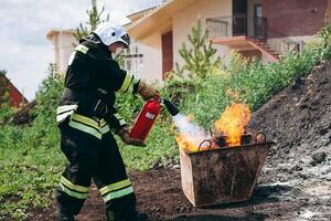 Fireman is extinguishing a fire at a building using a fire extinguisher photo