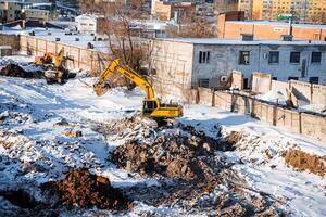 A Yellow Excavator Is Digging A Hole In The Snow photo