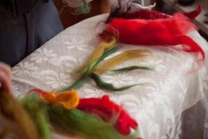 Person creating wool flower on table as art project photo