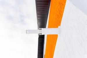 A white and orange building with a white gutter on the side photo