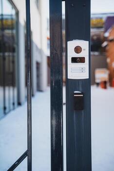 Black metal fence with modern door intercom system with camera and call buttons photo