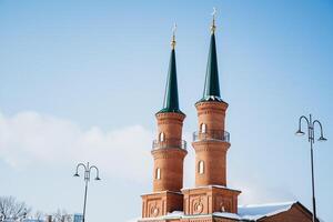 Two green and red minarets of a mosque. Blue sky in the background with some white clouds. photo